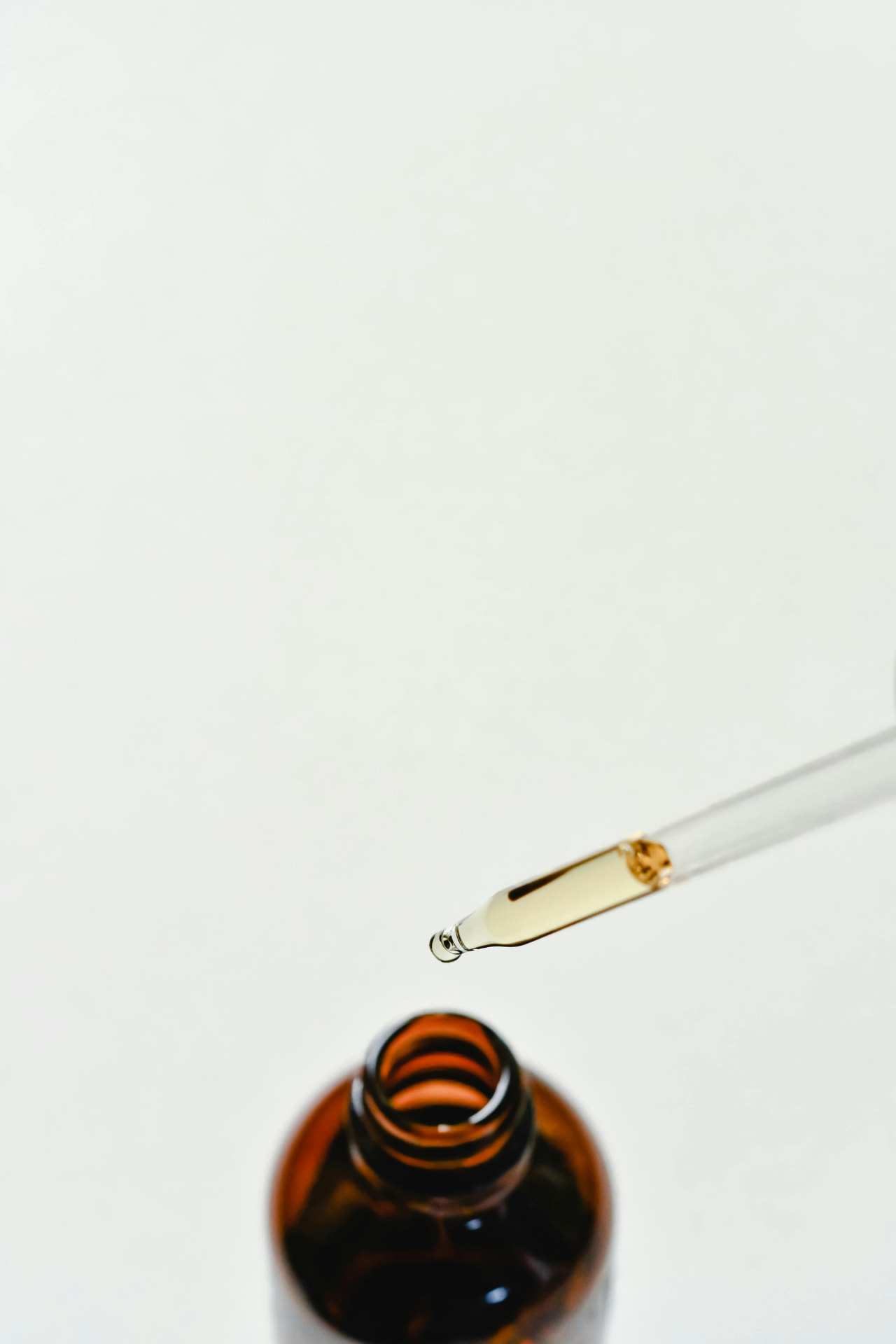 Pipette mit Öl über einer Braunglasflasche