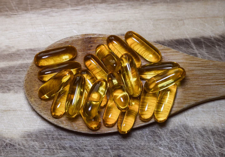 Vitaminkapseln auf einem Holzlöffel